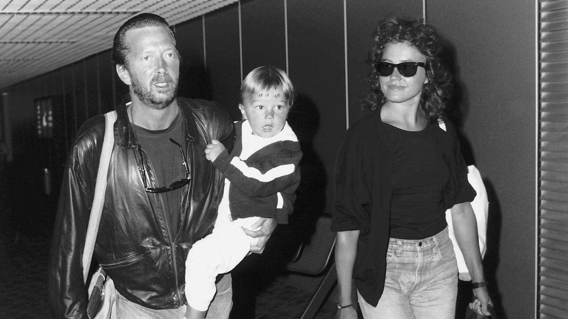 Eric Clapton singer songwriter and girlfriend Lori Del Santo walk through airport with son Conor